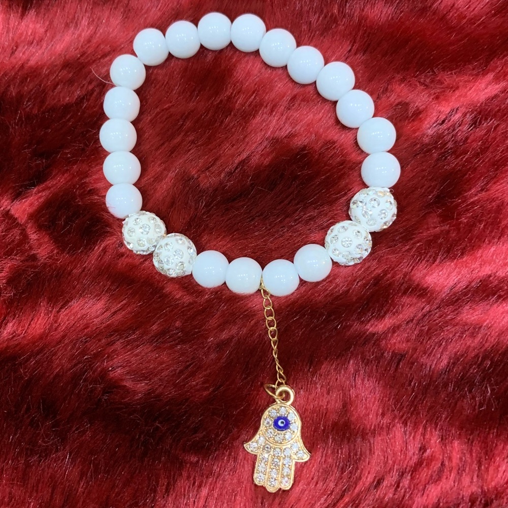 White beaded bracelet with hamsa hand hanging